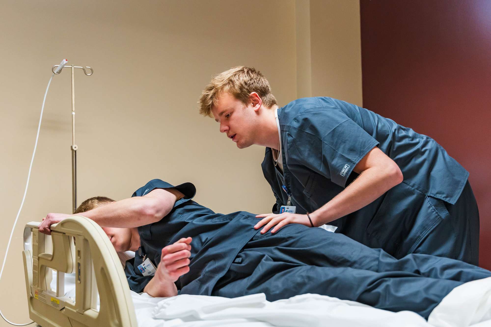 A Nursing Assistant is helping a patient move onto their side on a hospital bed.
