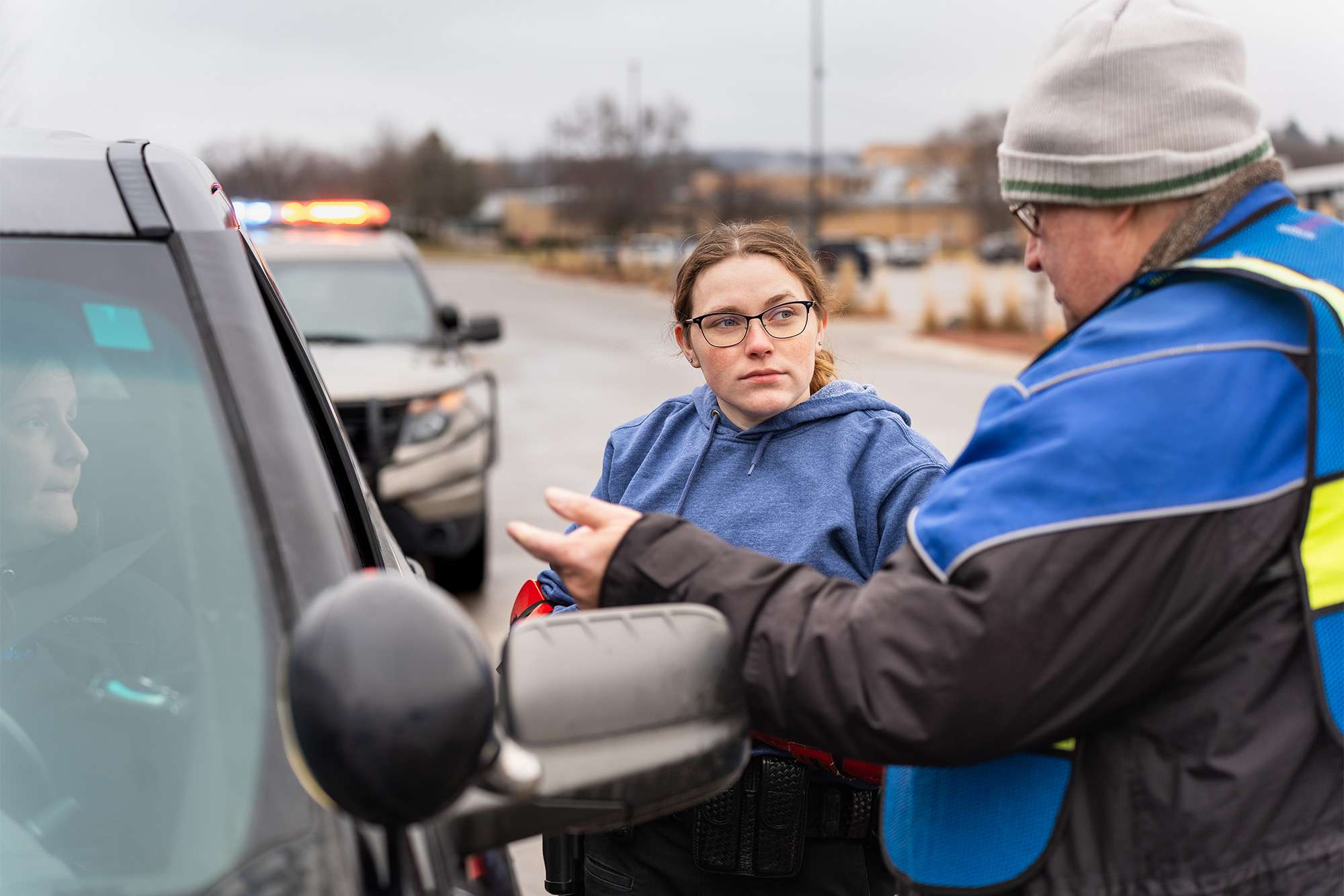 A trainee in a blue hoodie listens to an instructor during a law enforcement training exercise.