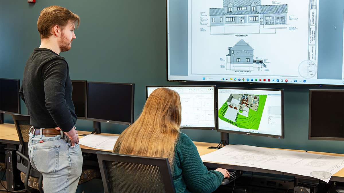 Architectural students collaborate on house design using computer-aided drafting software.