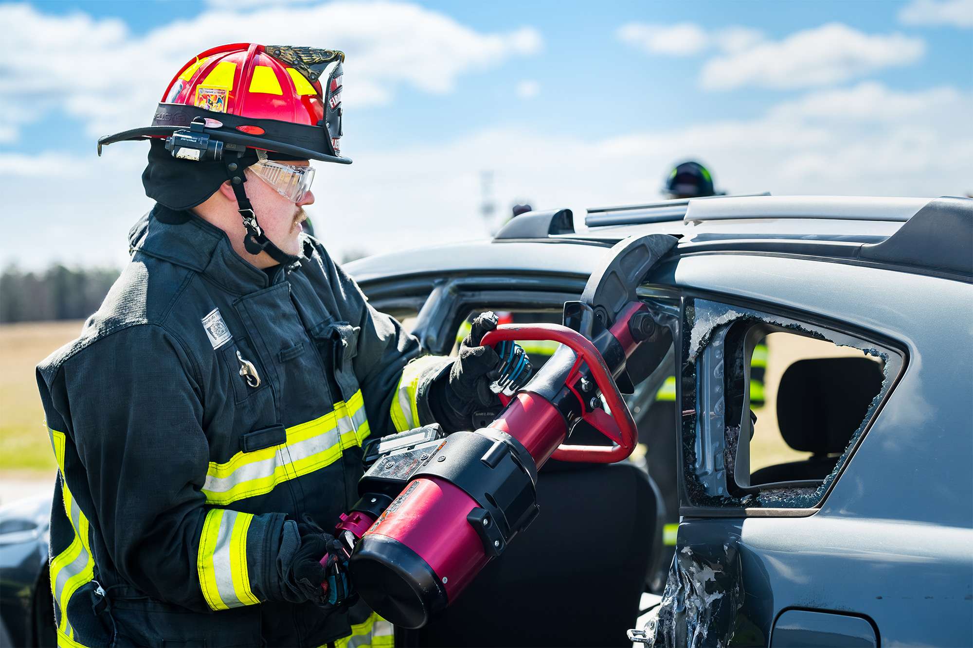Firefighter uses hydraulic rescue tool to cut open a damaged vehicle during extrication training.