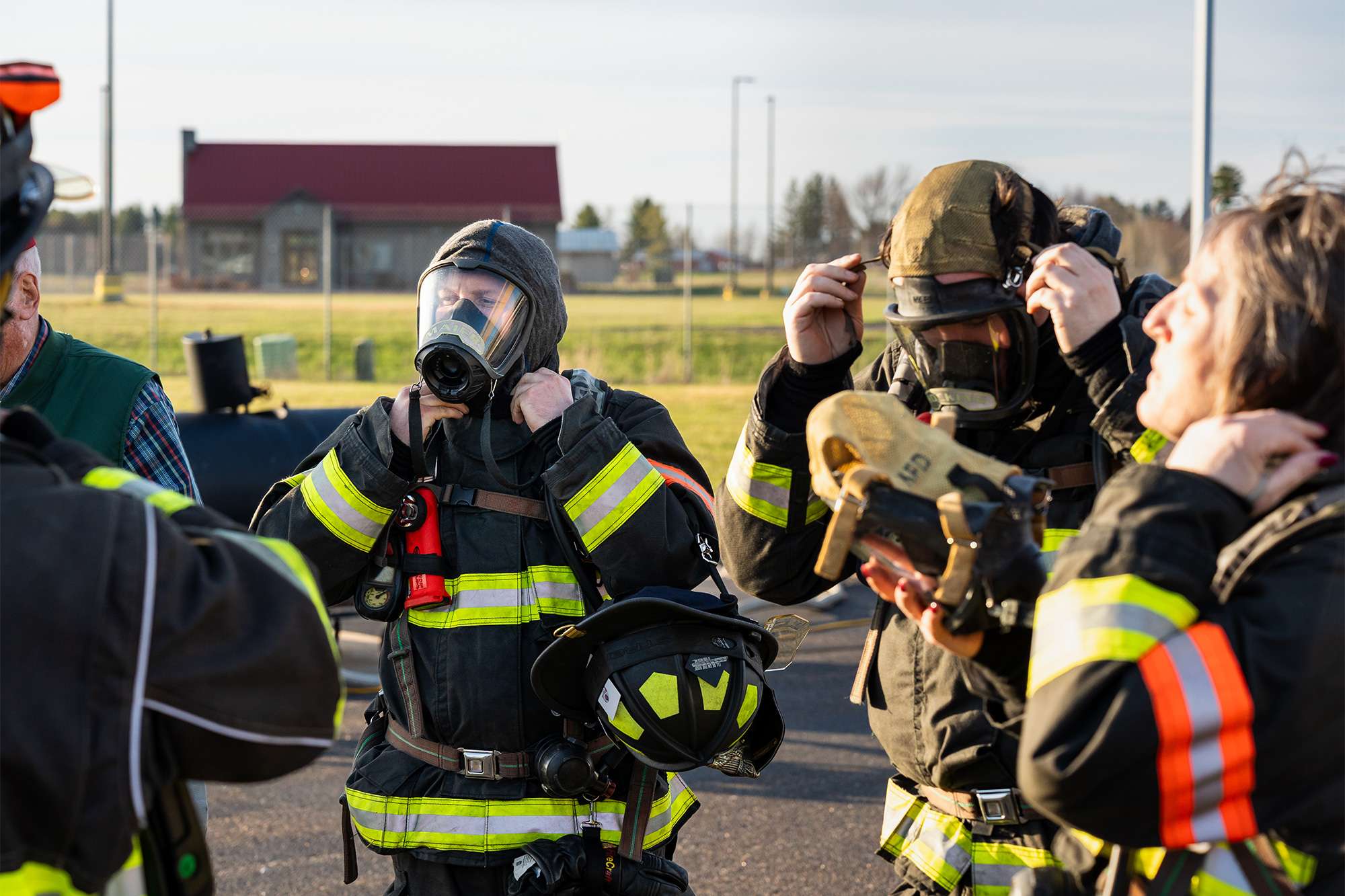 Firefighters adjust their protective masks and gear outside before beginning training.