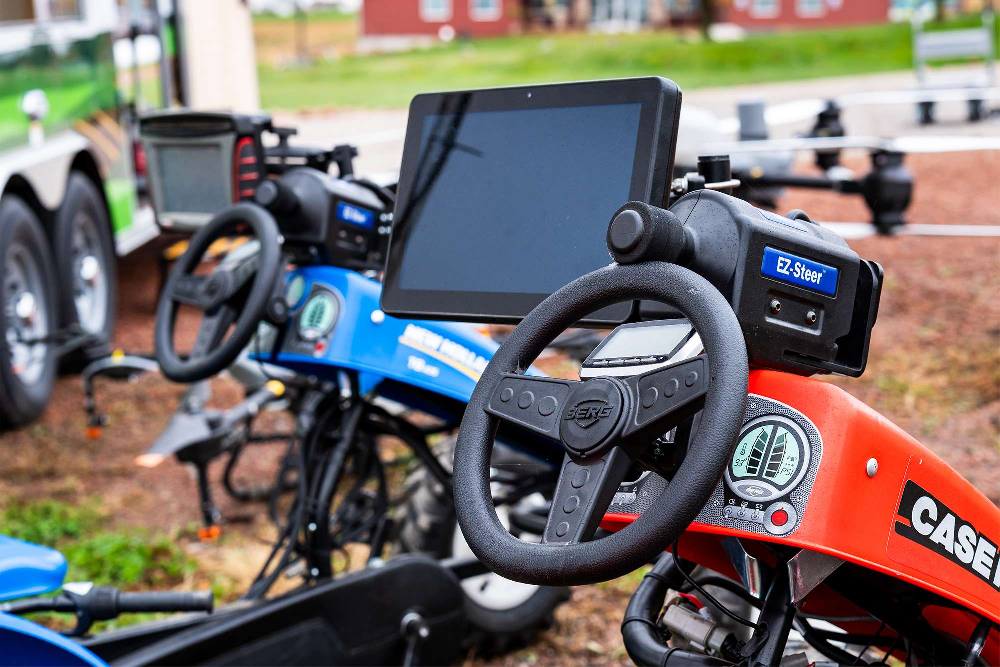 Row of compact ride-on tractors with steering wheels and dashboard screens, red and blue, CASE IH logo visible on the hood.